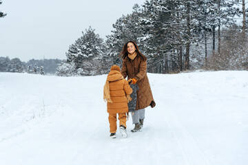 Woman with a little son on a winter hike in the snowy forest