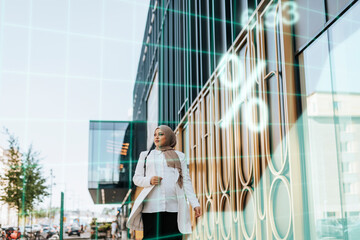 Young businesswoman walking along office building