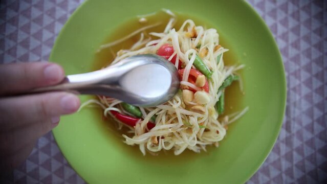 Close up of fresh yummy delicious Thai traditional popular street food spicy green papaya salad or Som Tam in green dish
