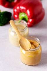 Glass Jars with Natural Baby Food on the Light Gray Background Vegetable Puree with Broccoli and Red Pepper Vertical