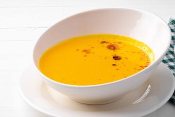 Pumpkin creamy soup served in bowl on white wooden background