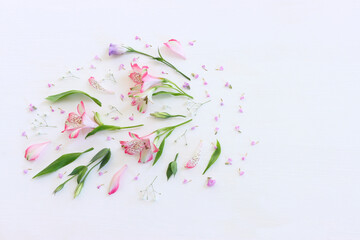 Top view image of pink and purple flowers composition over wooden white background .Flat lay