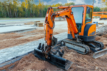 Mini excavator at the construction site. Compact construction equipment for earthworks.