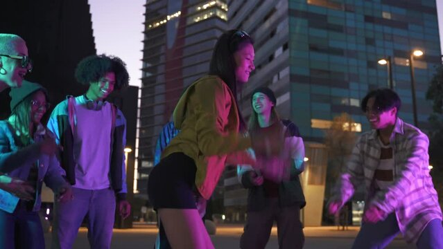 Young Asian Chinese Girl having fun dancing with group of Generation Z friends in music street party in the city at night