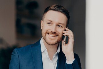 Smiling young man in suit using mobile phone at home