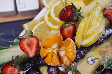 Raw fruits berries assortment platter on the white plate, on the table, selective focus
