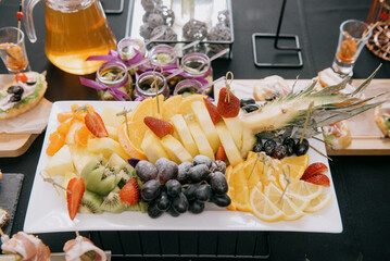Raw fruits berries assortment platter on the white plate, on the table, selective focus