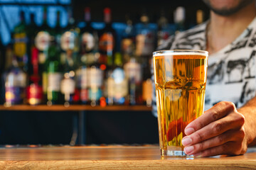 Barman serves glass of cold beer at bar counter in pub