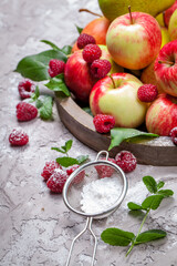 Fresh raspberries and apples on old wooden plate on a concrete background. Healthy concept. Natural healthy food. Organic food.