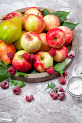 Fresh raspberries and apples on old wooden plate on a concrete background. Healthy concept. Natural healthy food. Organic food.