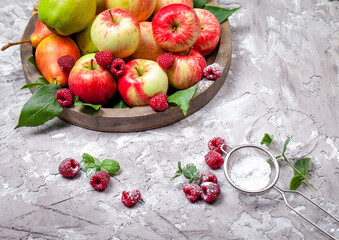 Fresh raspberries and apples on old wooden plate on a concrete background. Healthy concept. Natural healthy food. Organic food.