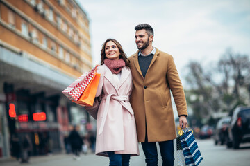 Obraz premium Couple of tourists walking in a city street and shopping together. People shopping fun concept