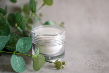 Obraz na płótnie Canvas Small transparent bottle of facial cream. Cosmetic and beauty product. Background with green plants.