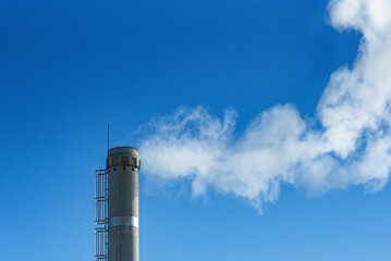 white smoke from pipe boiler room against background of blue sky