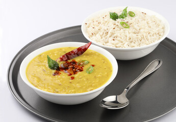 Indian popular food Dal fry or traditional Dal Tadka Curry or yellow lentil curry served with jeera rice in ceramic bowls on bamboo serving tray - obrazy, fototapety, plakaty