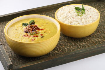 Indian popular food Dal fry or traditional Dal Tadka Curry or yellow lentil curry served with jeera rice in ceramic bowls on bamboo serving tray