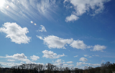 blue sky with clouds and dark forest