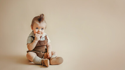 a kid in a brown vintage corduroy jumpsuit, shorts, knee socks sits on a beige background and eats cookies