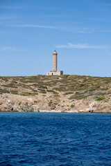 Lighthouse, stone and concrete beacon on hill at Ermoupolis port, Syros island, Greece.
