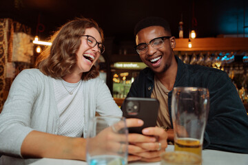 diverse friends out for dinner taking selfies and laughing 