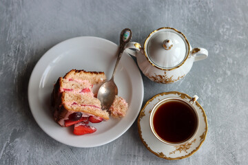 Piece of strawberry cake and cup of black tea on a table. Light grey background with copy space. Sweet food close up. 