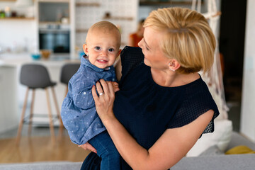 Naklejka premium Happy family indoors. Portrait of beautiful mother with cute baby playing smiling together.