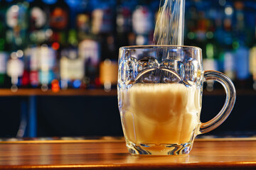 Pouring draft beer into a glass on bar background