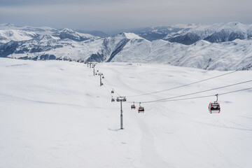 Fototapeta na wymiar Snowy slopes with gondola to Kobi and ski tracks in nice sunny day. Ski resort Gudauri, Georgia. Caucasus Mountains. Aerial view.