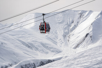 Fototapeta na wymiar Gondola (Ski Lift) against snow-covered Caucasus Mountains in Distance, Gudauri Ski Resort, Georgia