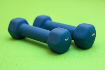 Naklejka na ściany i meble Close up shot of blue dumbbells against a bright green gym mat