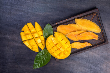 fresh and Dried sliced Mango, top view. Dried mango in wooden bowl and fresh mango fruit....