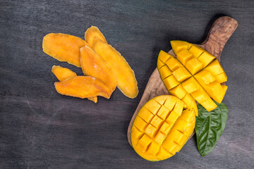 fresh and Dried sliced Mango, top view. Dried mango in wooden bowl and fresh mango fruit. Superfood, vegetarian food concept.