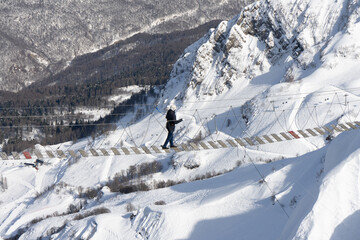 Person goes through the suspension bridge in mountains