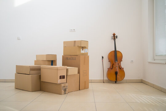 Cardboard boxes and cello in an empty room during moving in the new home
