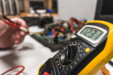 Detail of a multimeter being used by a technical IT on a computer motherboard