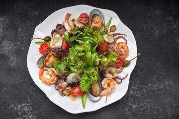Mix salad with seafood on a dark background