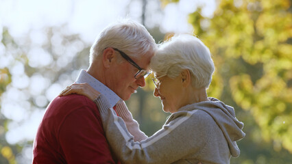 Portrait of aged Caucasian couple hugging in the park touching foreheads standing in the center of the shot senior people support concept selective focus copy space . High quality photo