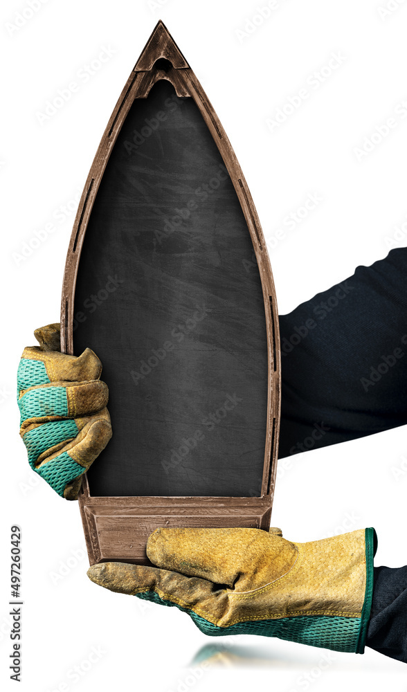 Poster hands with protective work gloves of a manual worker holding a small wooden boat with a blank blackb