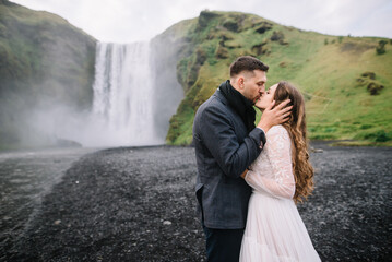 Fototapeta premium Stylish Bride and groom on elopement near Skogafoss waterfall. Iceland wedding 