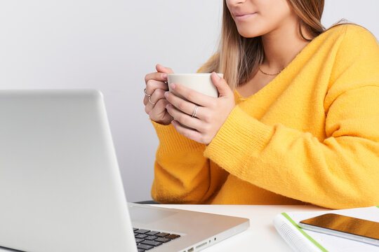 Girl In Unrecognizable Yellow Sweater Drinking Coffee While Working On Laptop Computer