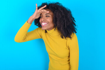 Young woman with afro hairstyle wearing yellow turtleneck over blue background very happy and...