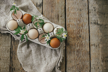 Happy Easter! Easter rustic still life. Natural easter eggs with blooming spring flowers in tray on rural wooden table. Space for text. Simple stylish festive decoration on table