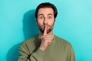 Photo of silent beard young guy finger mouth wear khaki sweatshirt isolated on teal color background
