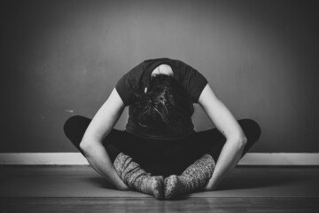 Grayscale shot of a young female practicing yin yoga in a studio - obrazy, fototapety, plakaty