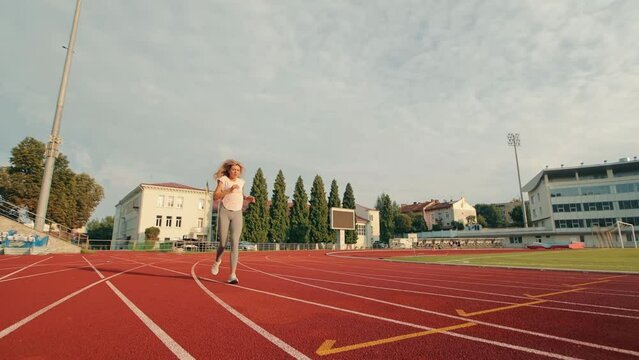 Athlete who finishes sports and runs to the finish line. Stop runner woman and take deep breaths and breathe evenly. Running in a backpack at the stadium.