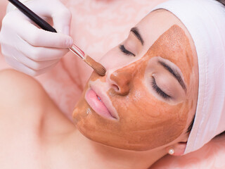 Woman getting facial mask, beauty treatment and skincare in modern beauty spa