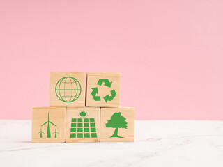 World Earth day concept. Wooden cubes with eco-friendly icons over a marble floor against a light pink background