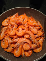 Orange tasty fried shrimps on a frying pan. Vertical indoor shot. High quality photo