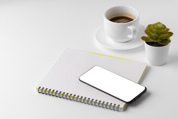 Fototapeta na wymiar Creative white table with blank cellphone and supplies