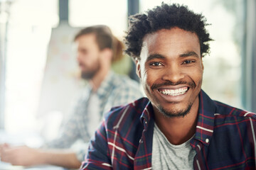 Let me help you find the right business solutions. Portrait of a young businessman sitting in a modern office with his colleagues.